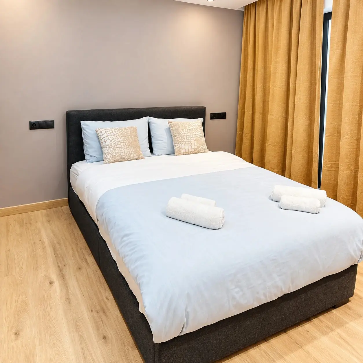 Double bed with fresh towels and golden curtains in Agatha 4